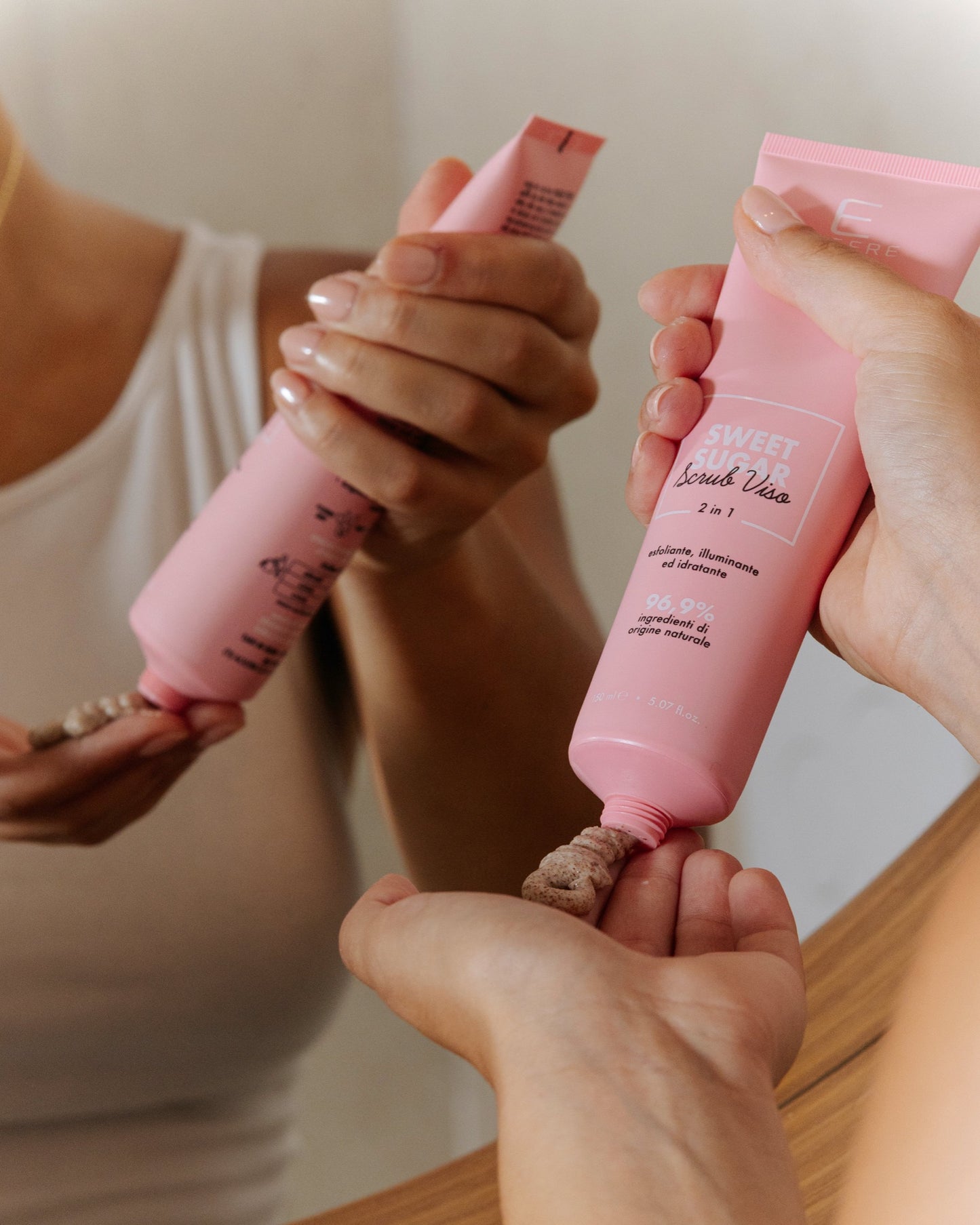 Mani che spremono il tubo dello scrub viso Sweet Sugar Essere Bio per dosare il prodotto sul palmo