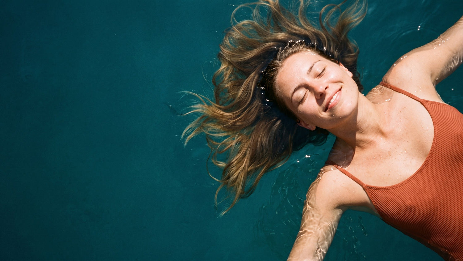 Primo piano di una donna che galleggia sorridendo in mare turchese