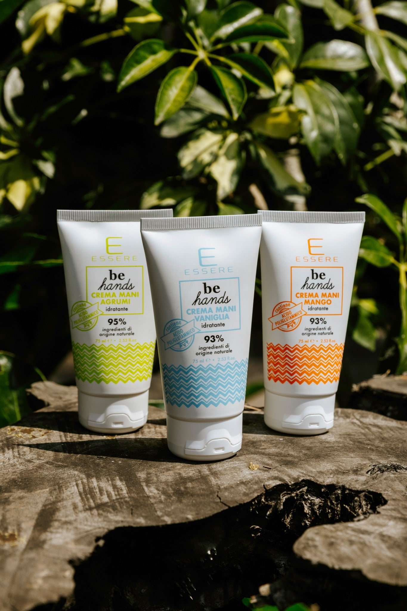 Le tre Creme Mani Be Hands Essere Bio, mango agrumi e vaniglia, in tubo su un tronco tra la vegetazione