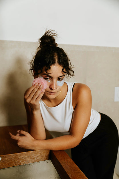 Donna applica la maschera contorno occhi Deja Blue Essere Bio davanti allo specchio, gesto beauty