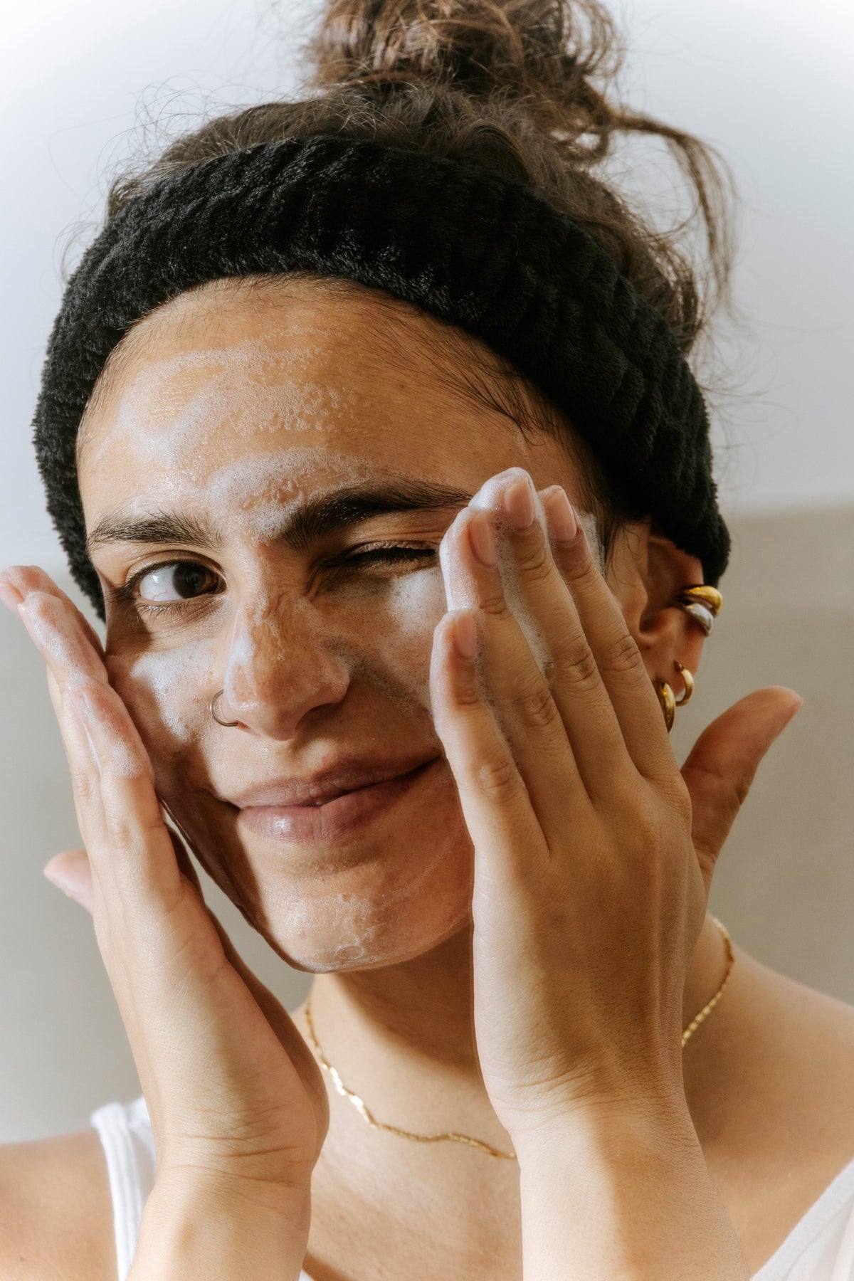 Woman cleansing her face with Essere Bio My Cloud mousse, a soft, gentle foam on the skin