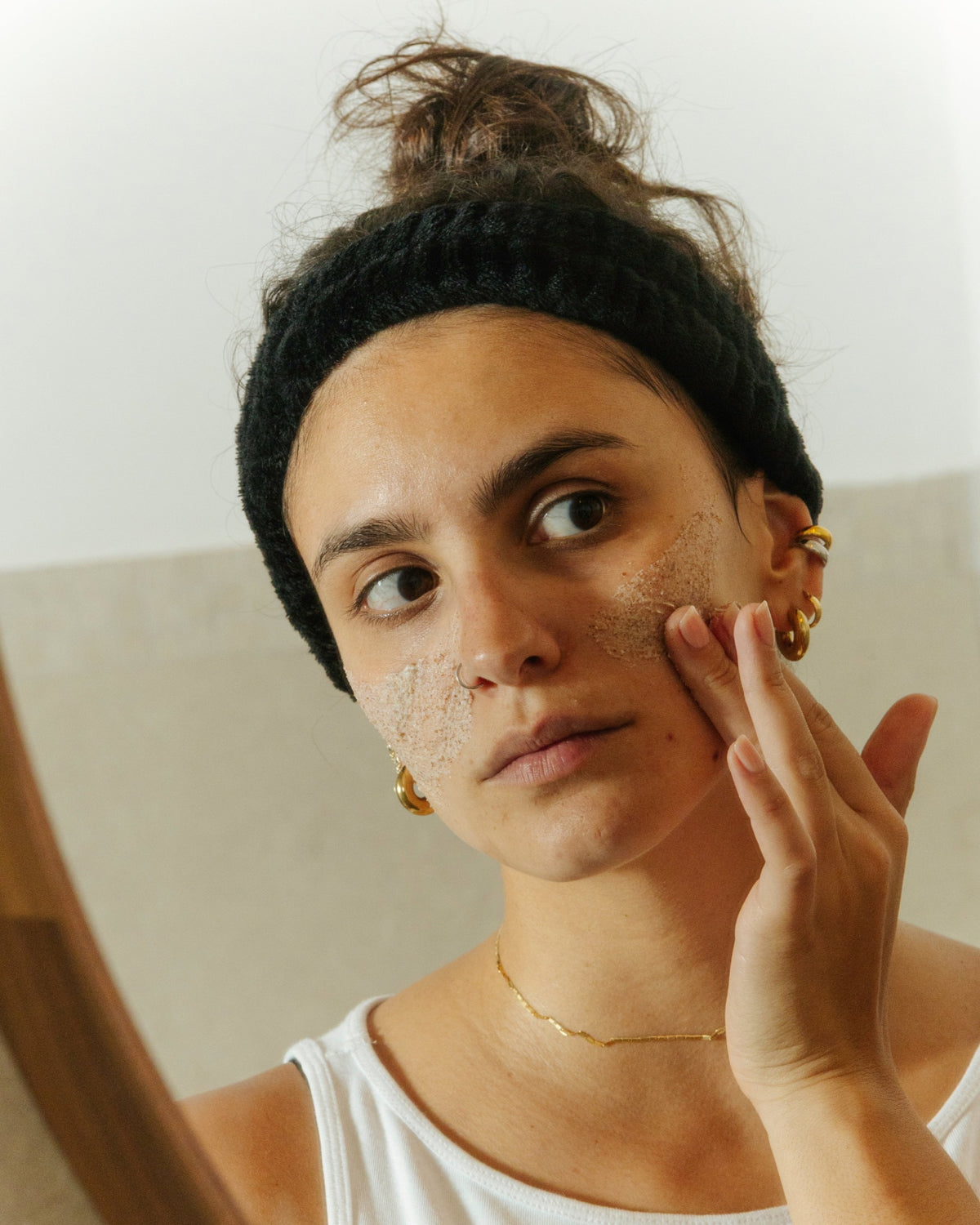 Woman applying the Essere Bio Sweet Sugar face scrub to her cheek with gentle circular movements