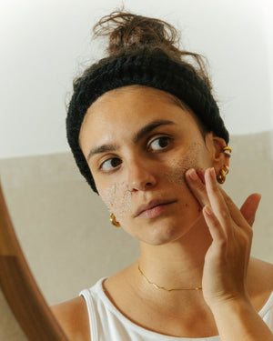 Woman applying the Essere Bio Sweet Sugar face scrub to her cheek with gentle circular movements